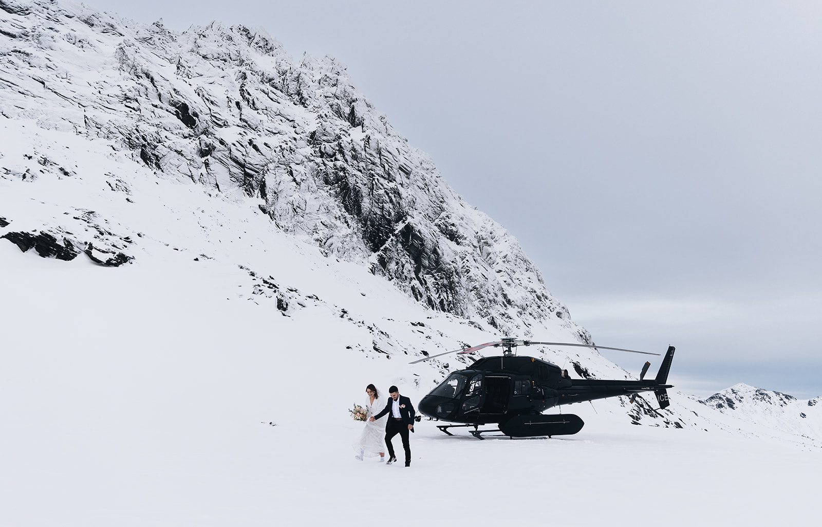 Squamish elopement — couple stepping out of a helicopter on a snowy mountain